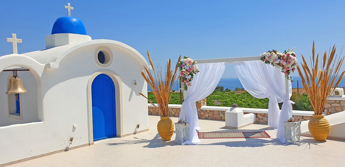 Blue-domed chapel with a white ceremony arch on the caldera