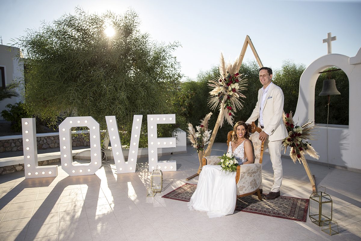 Ceremony arch beside illuminated LOVE letters at a Santorini chapel