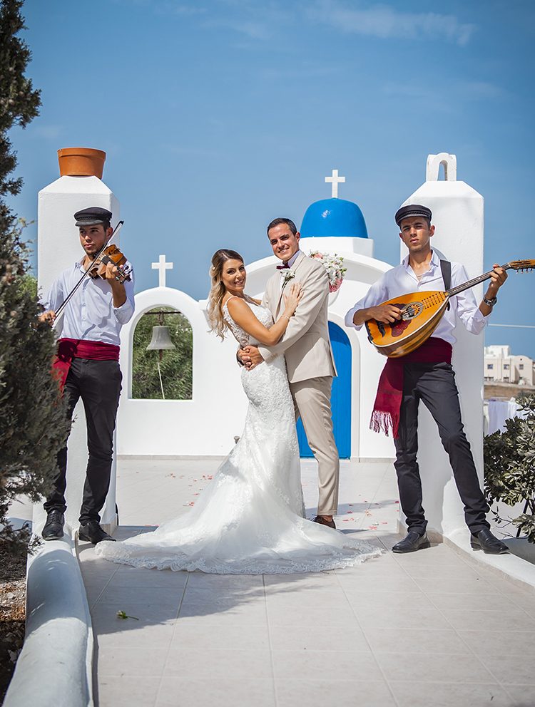 Traditional Greek musicians playing at a blue-domed chapel