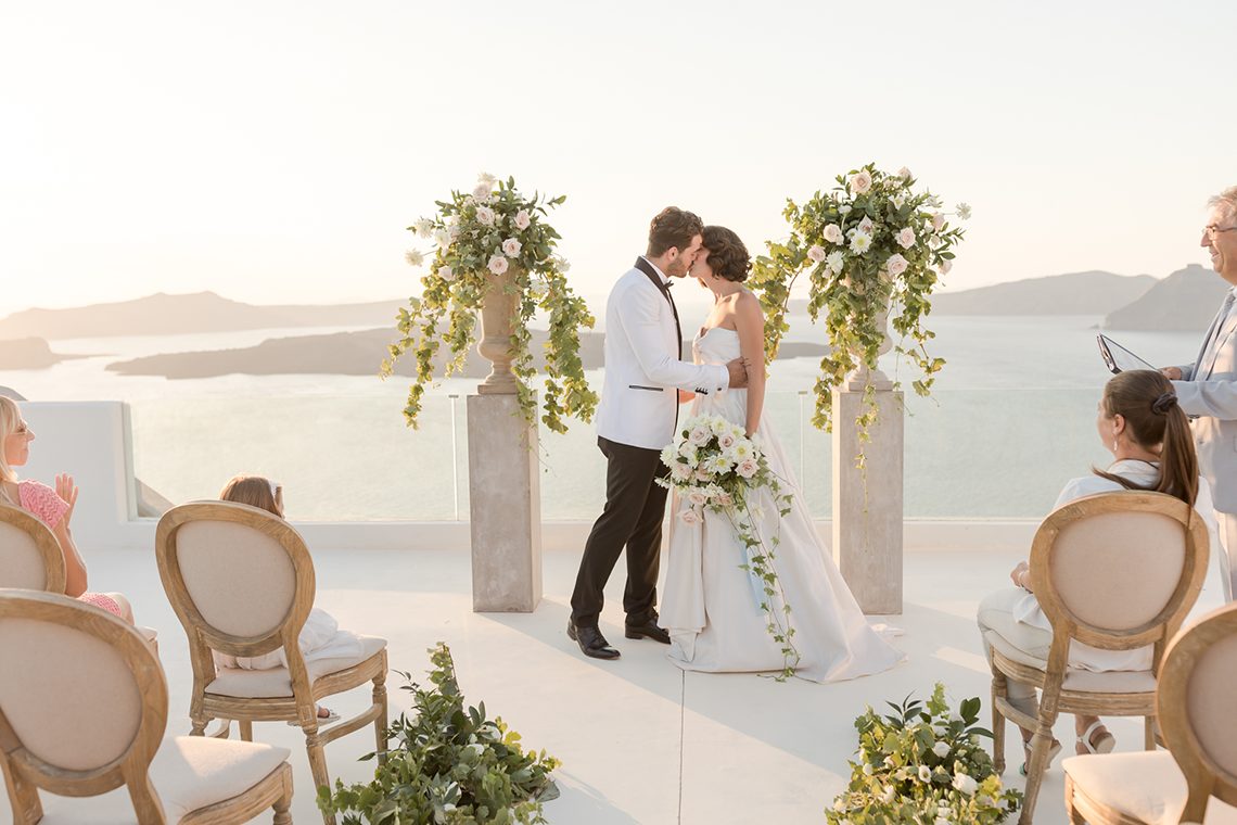 Small wedding party gathered for a golden-hour ceremony above the caldera