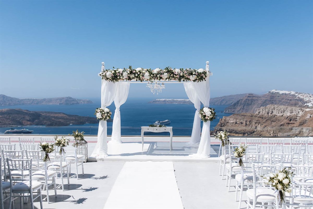 White wedding gazebo dressed with roses on a Santorini terrace above the Aegean