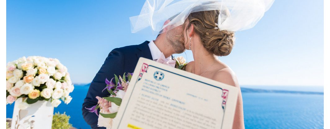 Couple holding their Santorini marriage certificate