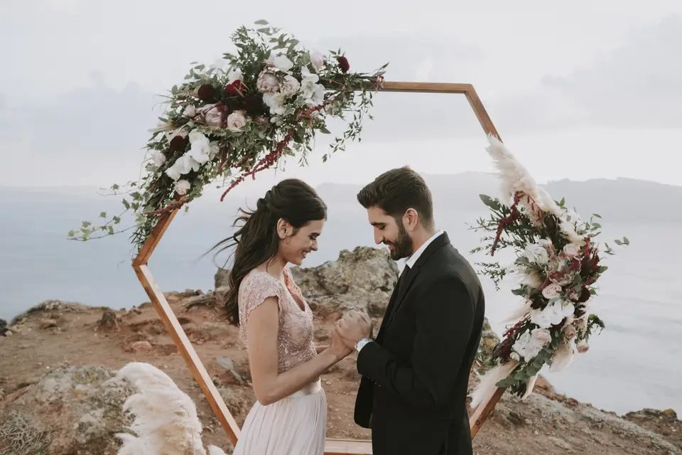 Couple beneath a floral arch on the cliff edge
